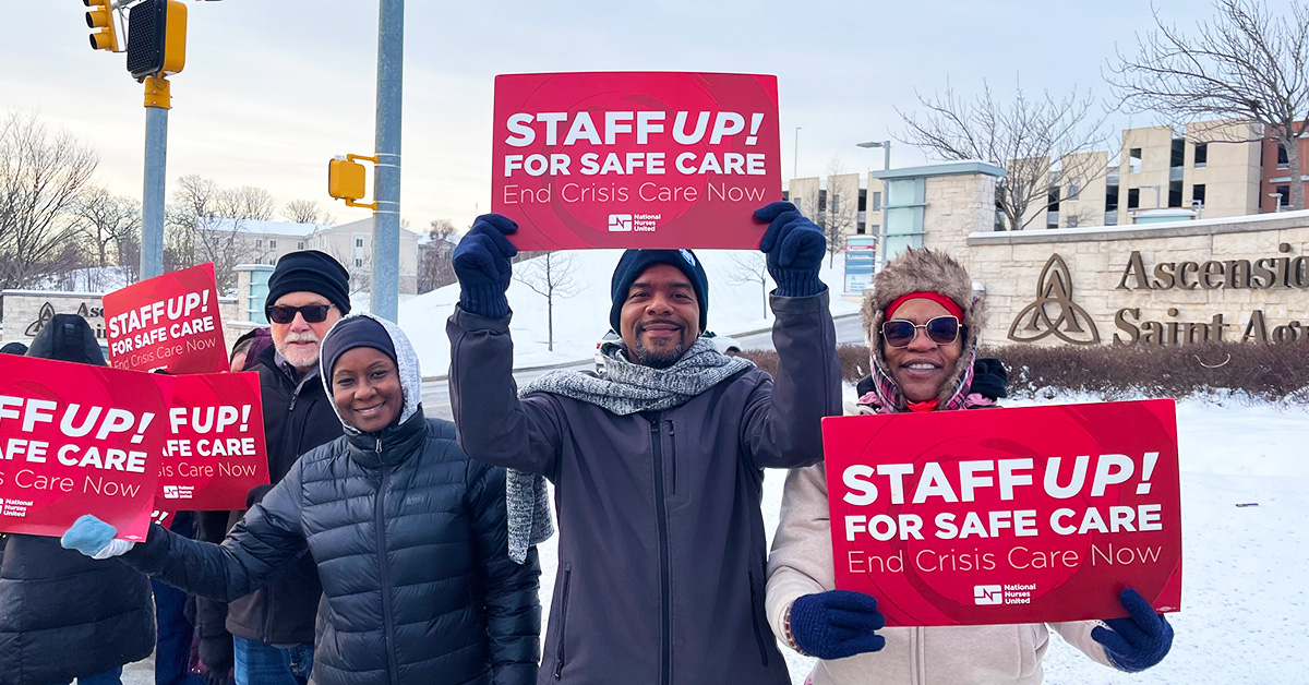Group of 3 nurses outside in cold weath holding signs "Staff Up For Safe Patient Care"