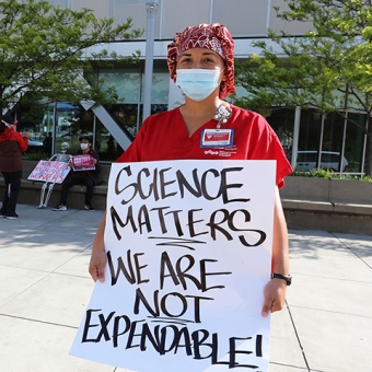Nurse holds sign "Science Matters, We Are Not Expendable"