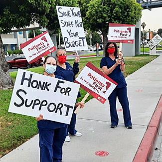 Nurses holding signs: "Honk for support" "Patients first in the hospital" and "Save your staff, not your budget"